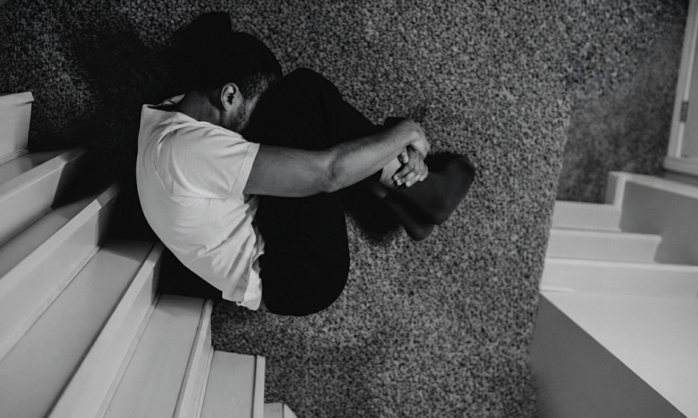 A person curled up in emotional distress and nervous system freeze, representing the heavy toll of unmanaged emotional patterns in relationships.